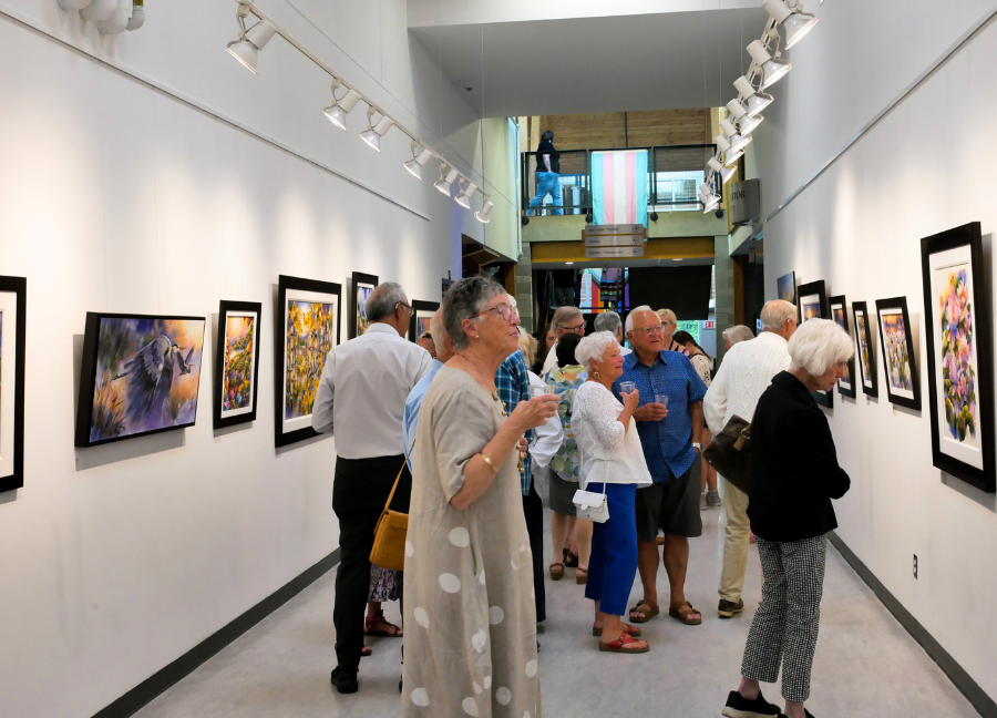 A group of galley attendees gather in the Alex Fong gallery to experience his art. Conversations are going on in the background and others examine the artwork