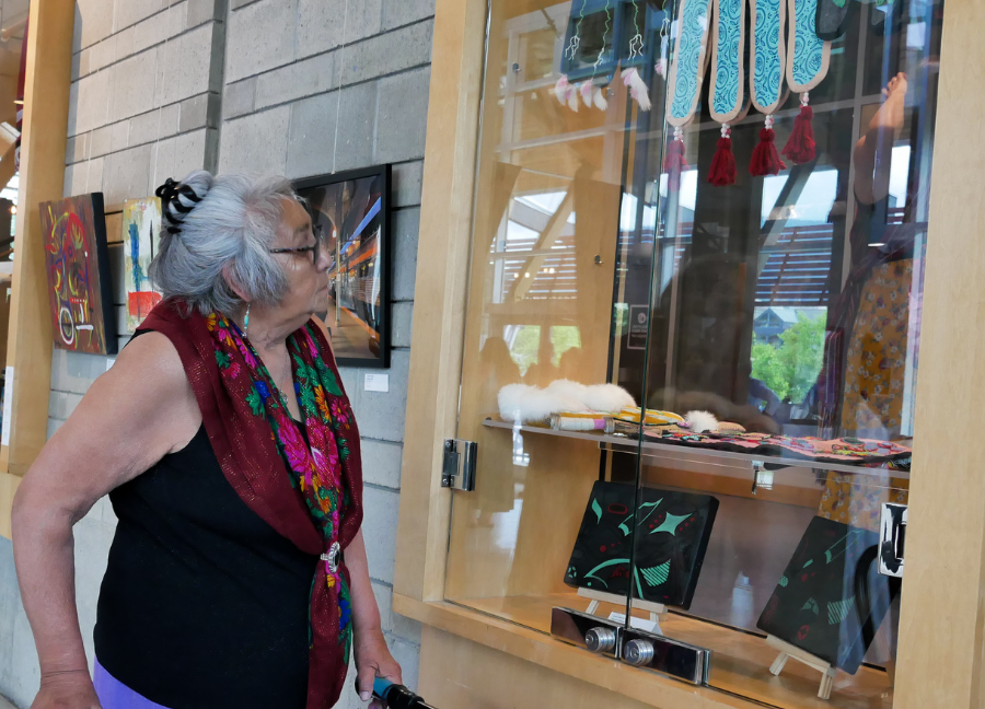 Elder Dorothy walks along the cabinets filled with artwork by the Ki Low Na Society